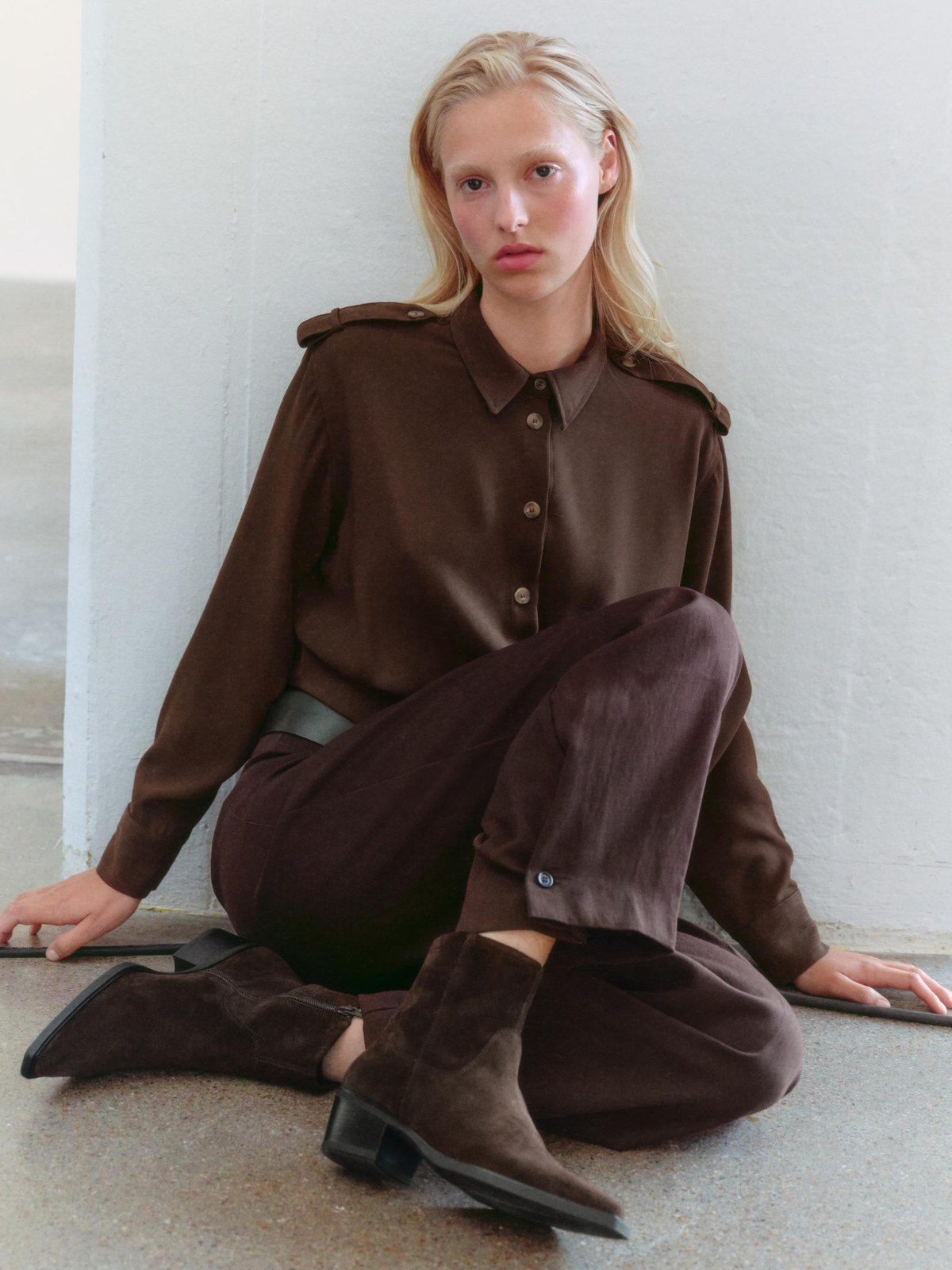 Woman in a brown outfit and suede Vagabond boots seated on the studio floor