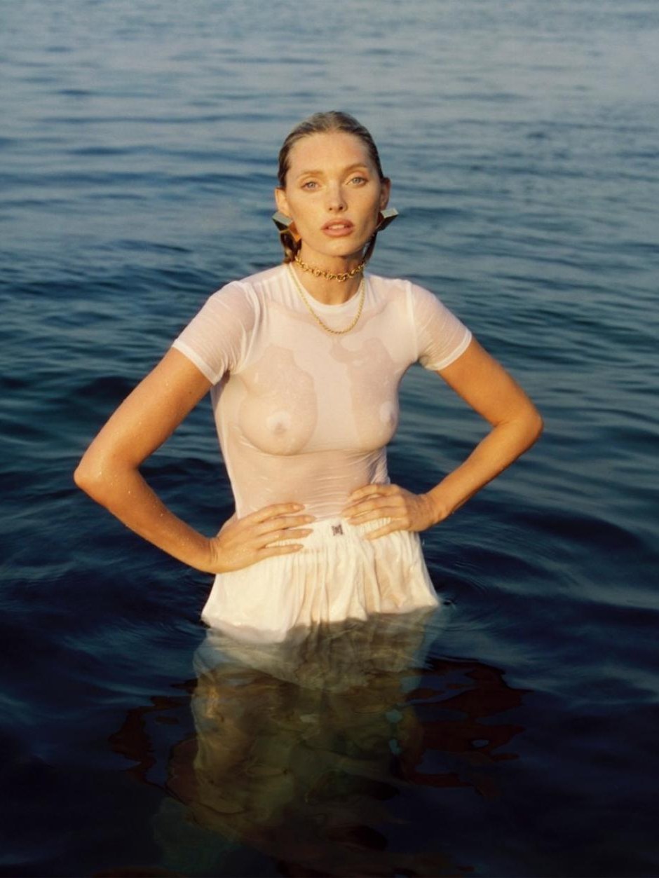 Model in an ivory top and skirt standing at the water's edge