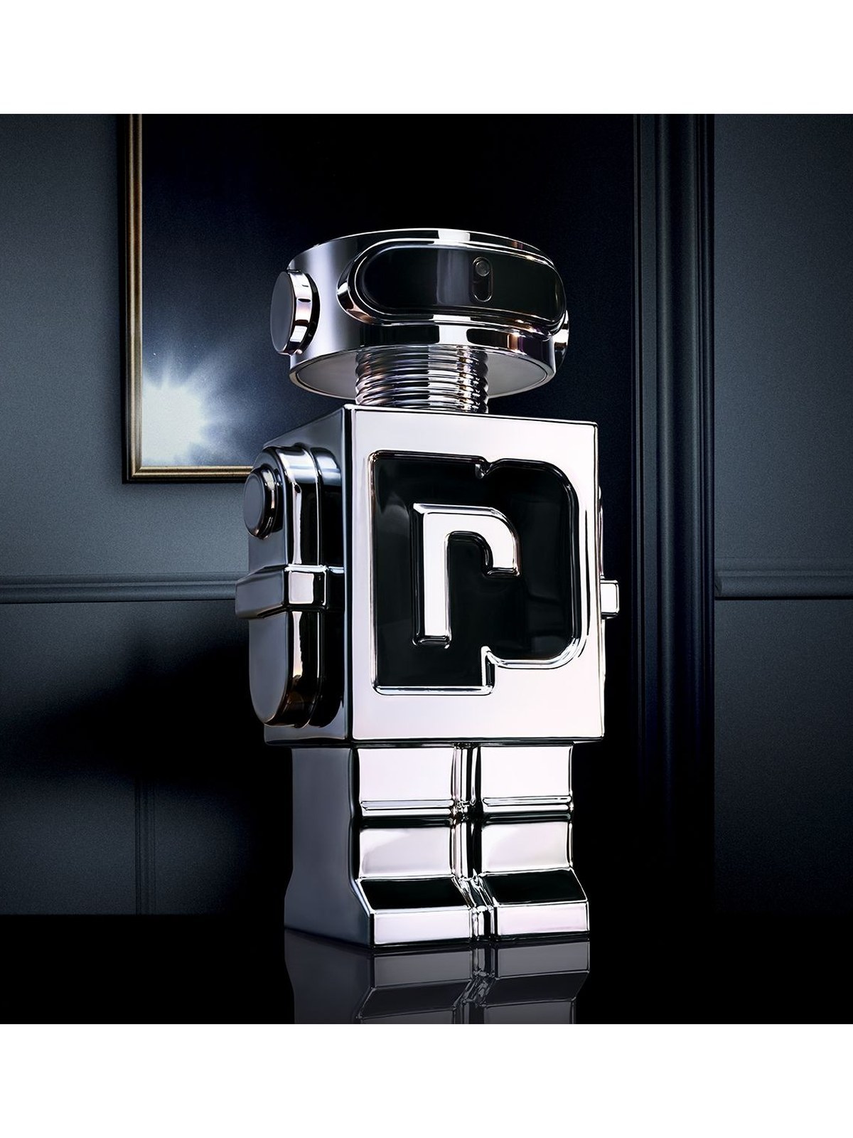 Chrome Rabanne Phantom robot bottle with a black P on its chest against a dark blue wall with a framed picture