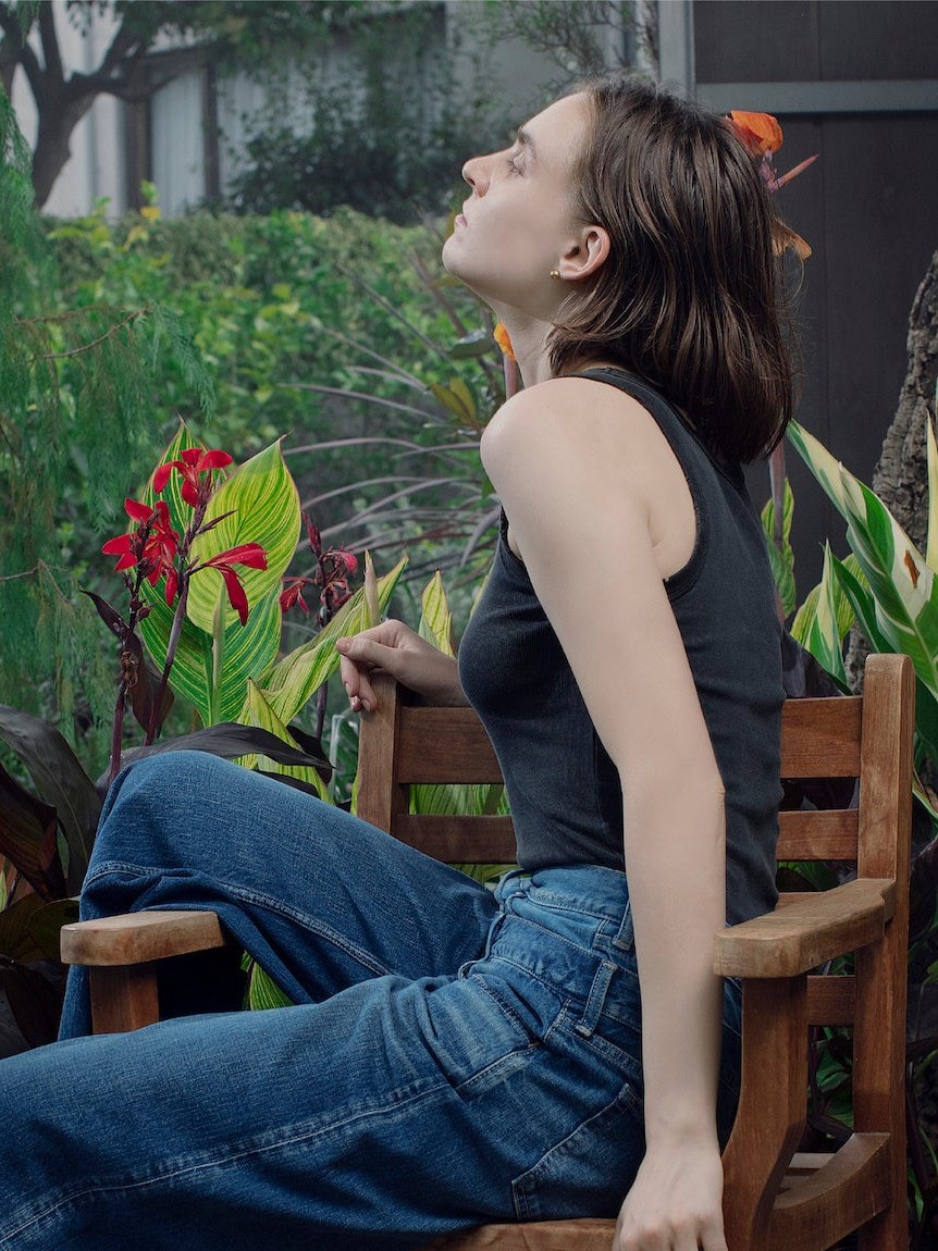 Model seated in blue jeans on a courtyard chair