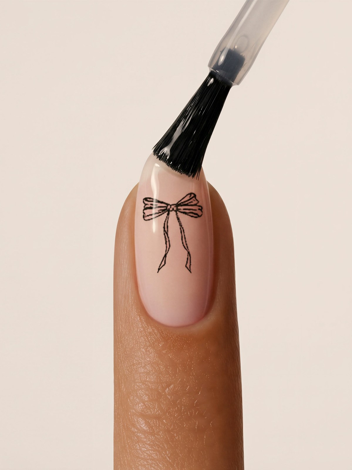 A bow motif being applied to a fingernail with a small brush