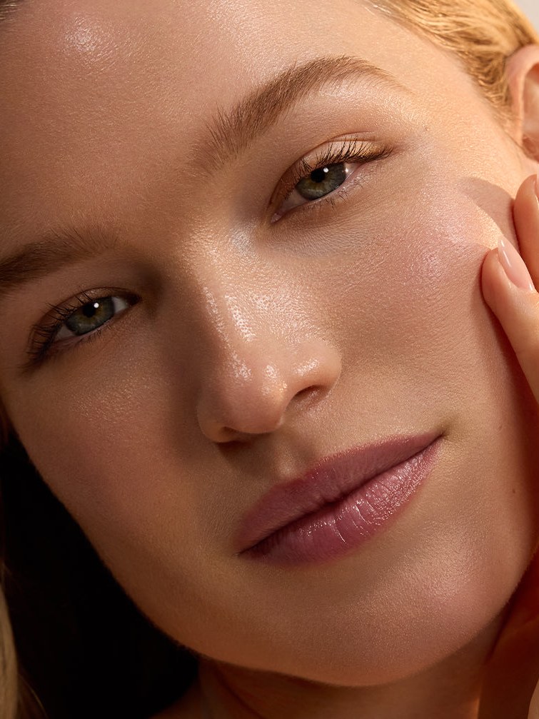 Close portrait of a woman with dewy skin in warm natural light
