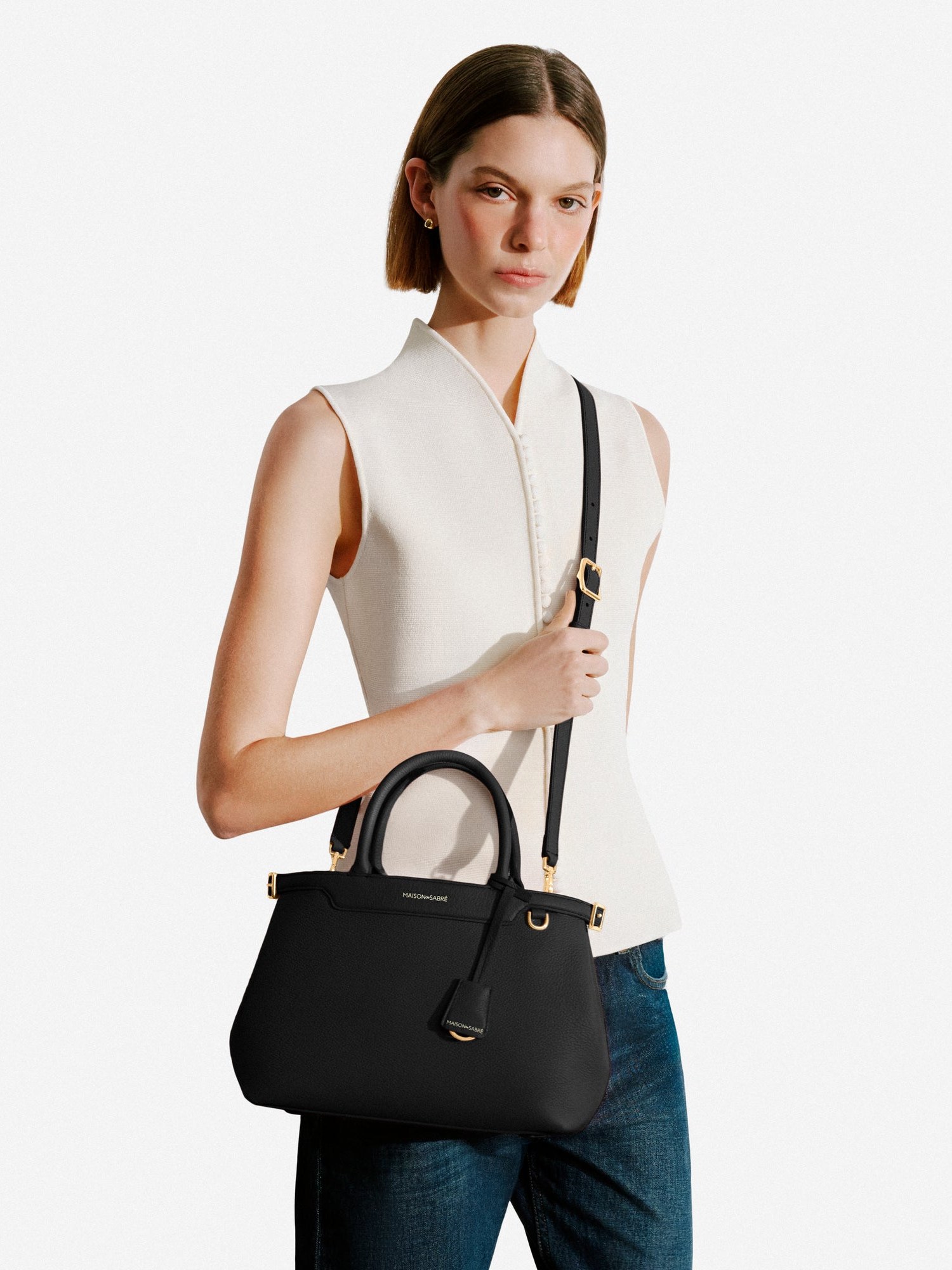 Model with a black Palais bag across the body against grey