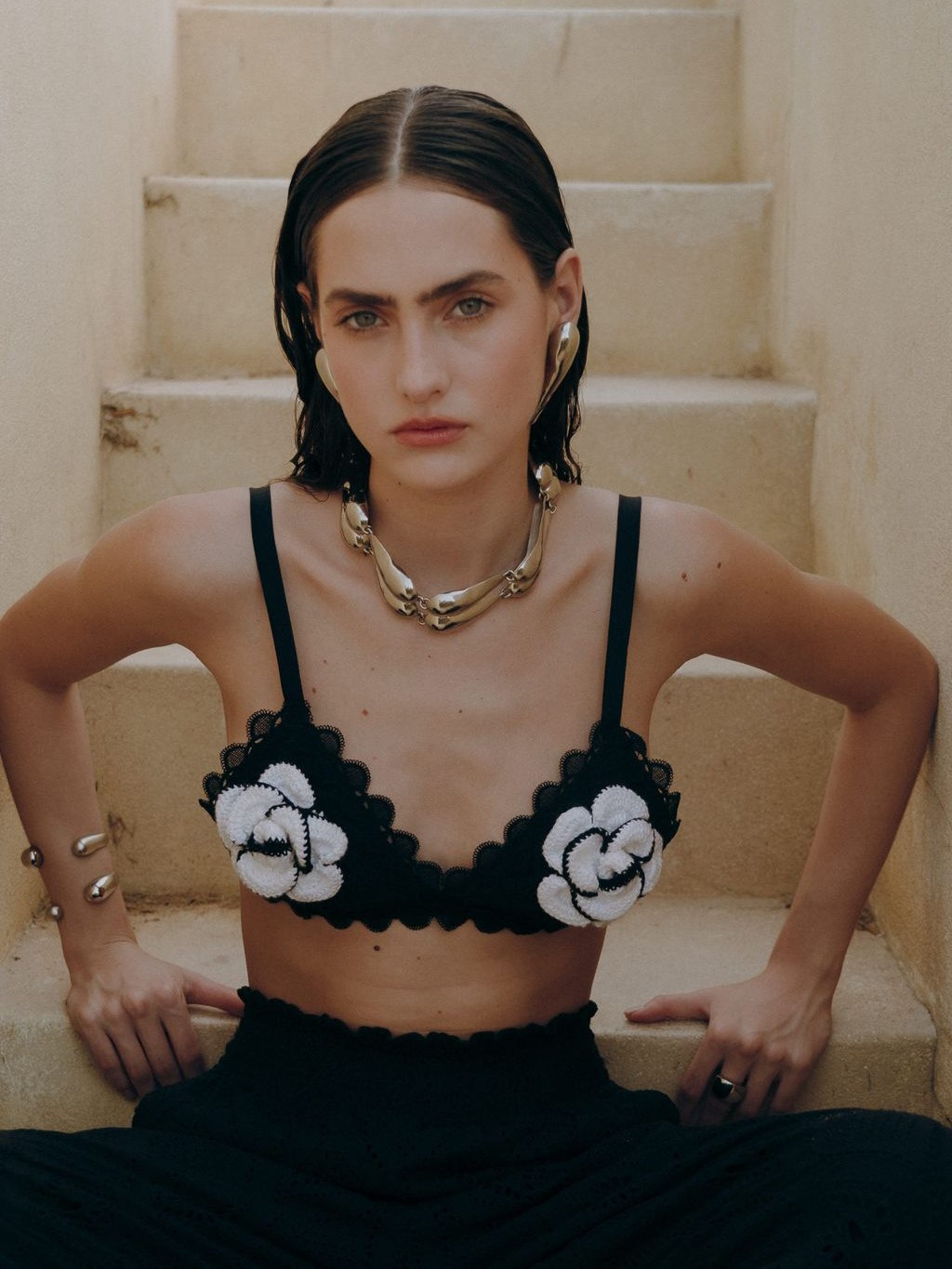 Model in an embroidered black and white top on stone steps.