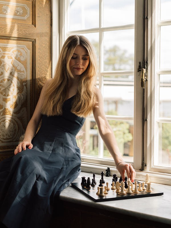 Anna Cramling plays chess beside a sunlit window