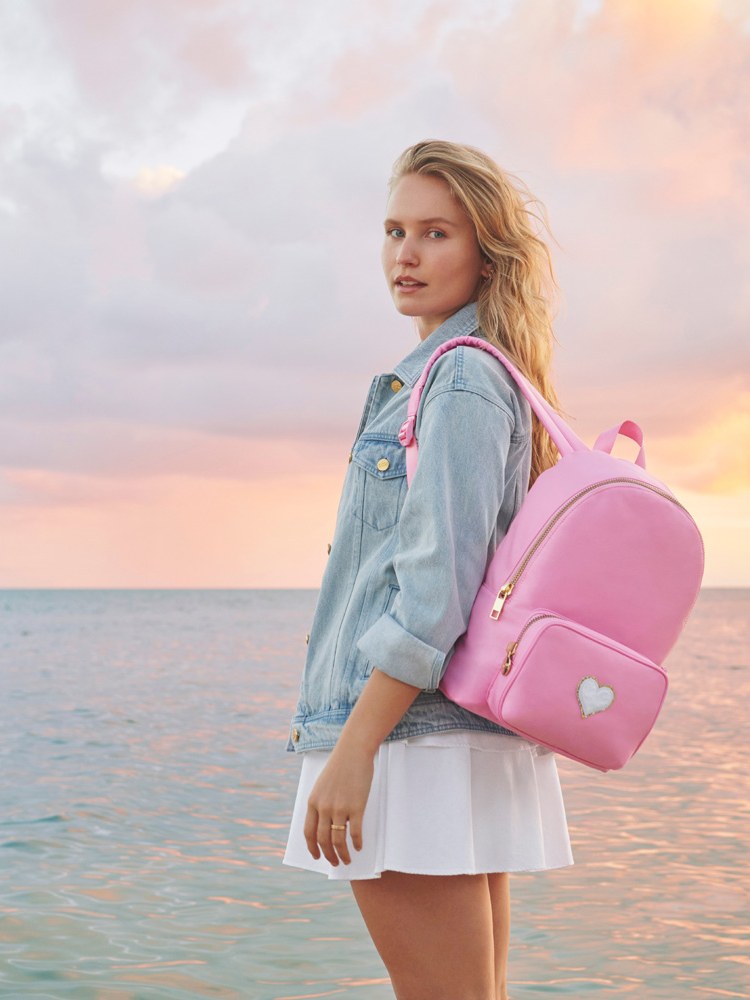 Model with a pink backpack by the water at sunset