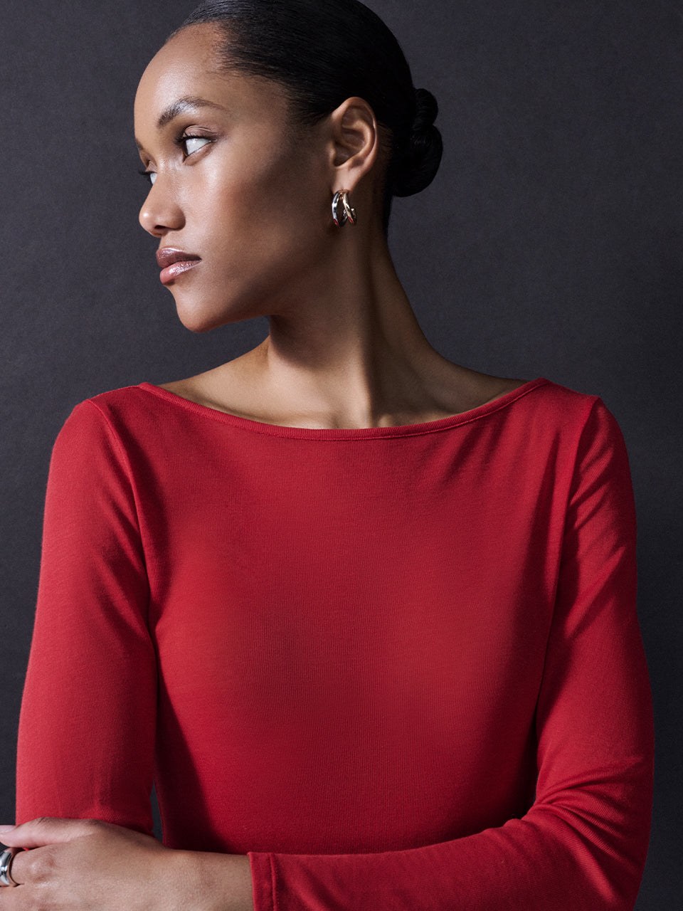 Model in a red top against a dark studio backdrop