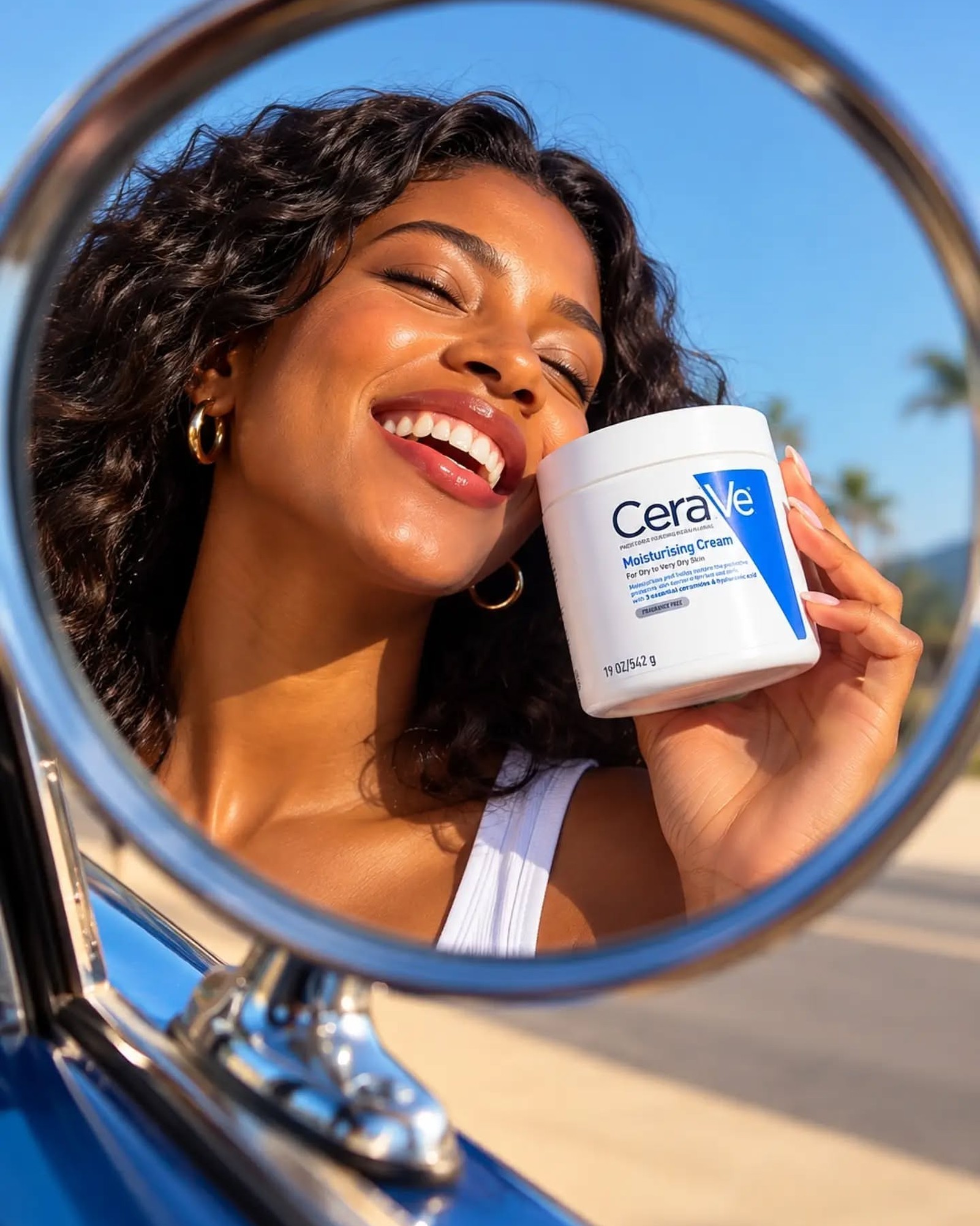 Smiling woman with dark wavy hair and gold hoops reflected in a round car mirror holding a CeraVe Moisturising Cream tub under a blue sky with palm trees