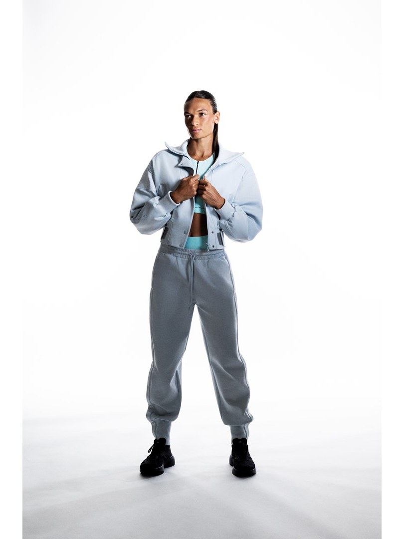 Anna Hall in an icy blue jacket and gray trousers in a full length studio portrait