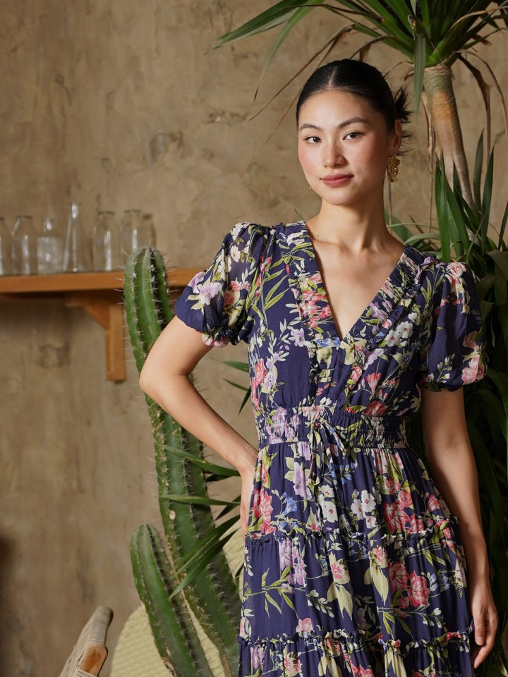 Model in a purple floral dress in a plant-filled interior