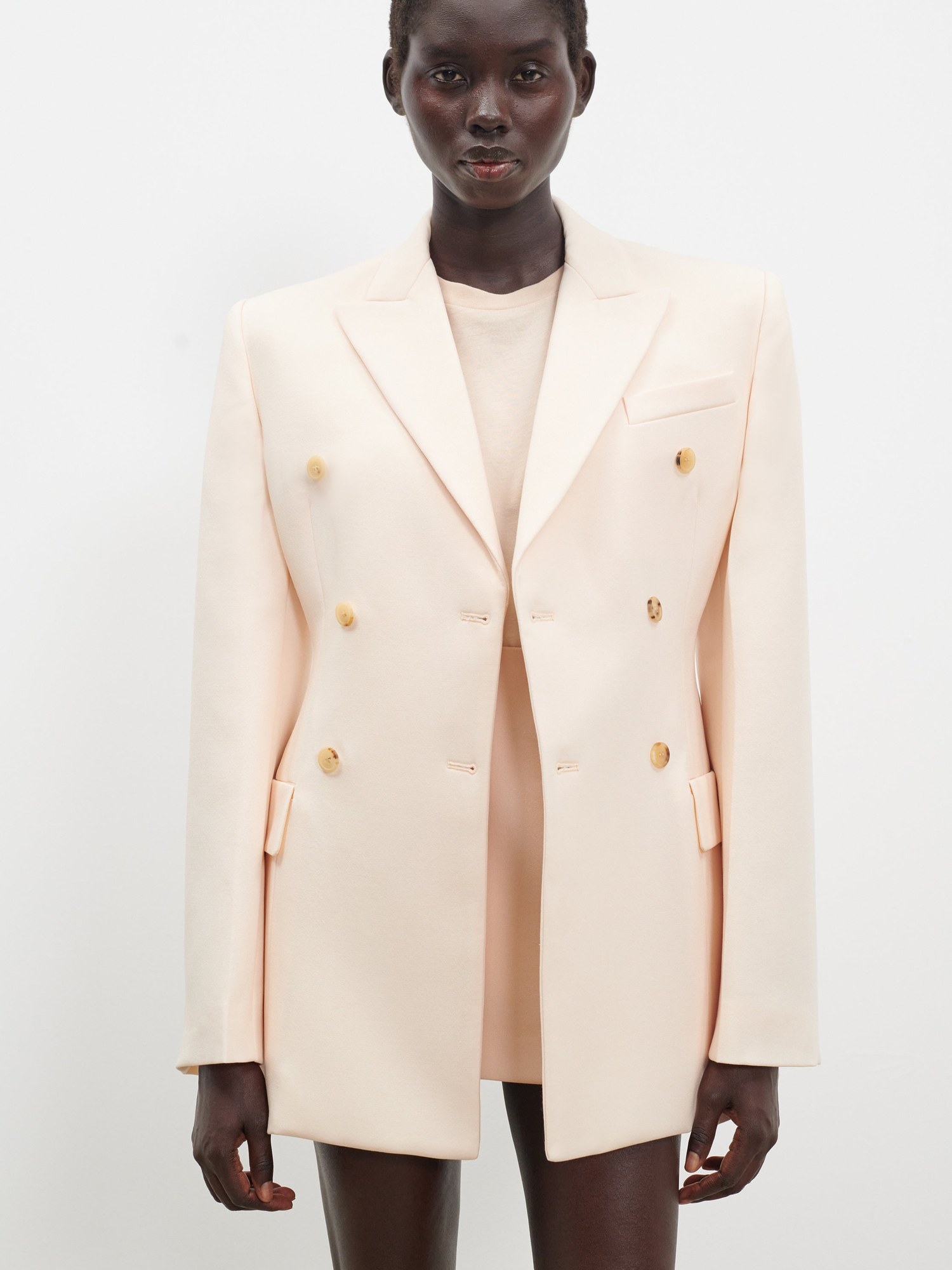 Close crop of a model in a cream double breasted blazer with gold buttons