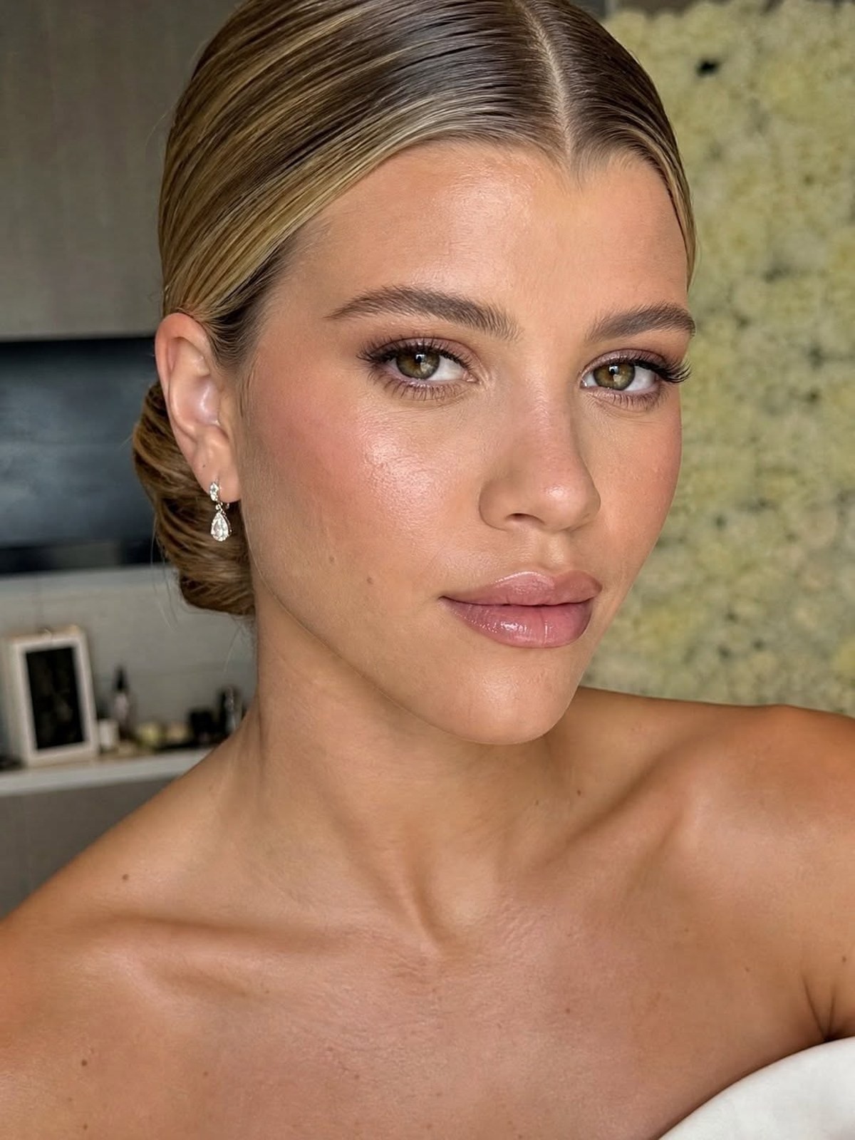 Close up of model's face with soft blush, sleek hair and glossy nude lips