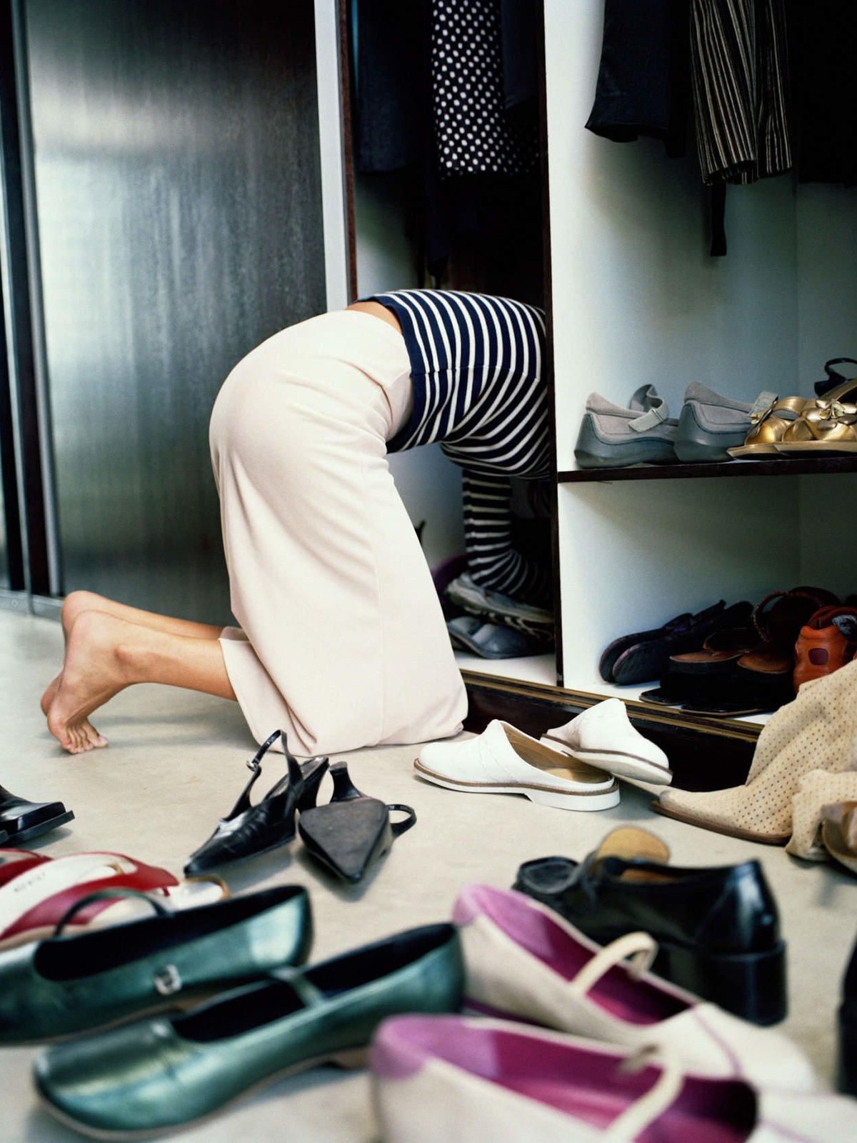 A woman on the floor sorting through a pile of shoes
