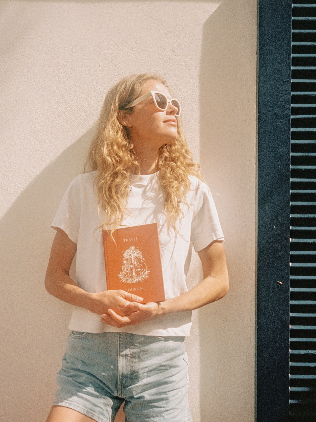 Woman in sunglasses holding an orange Papier notebook outdoors