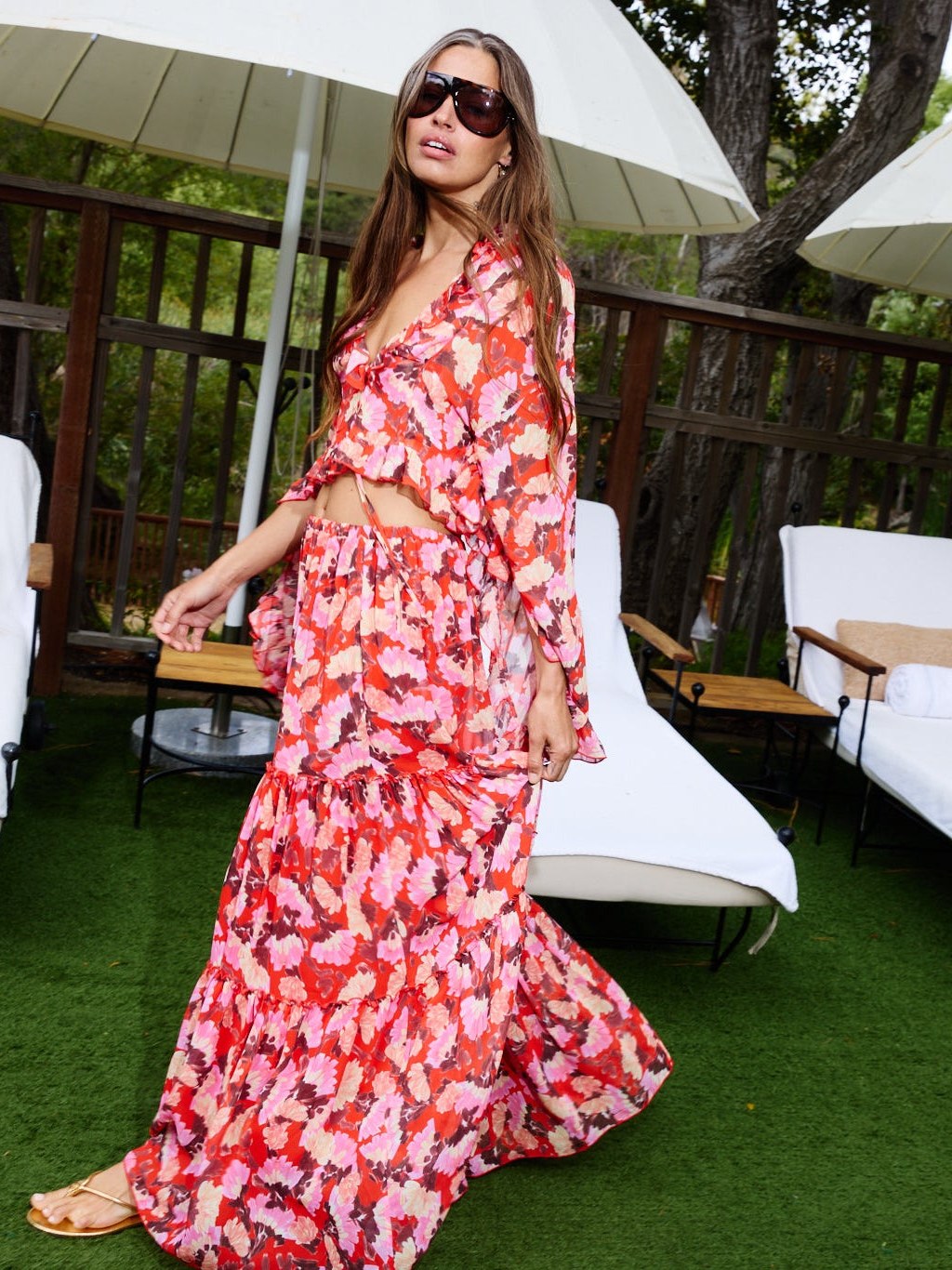 Model in a red floral maxi dress by pool loungers