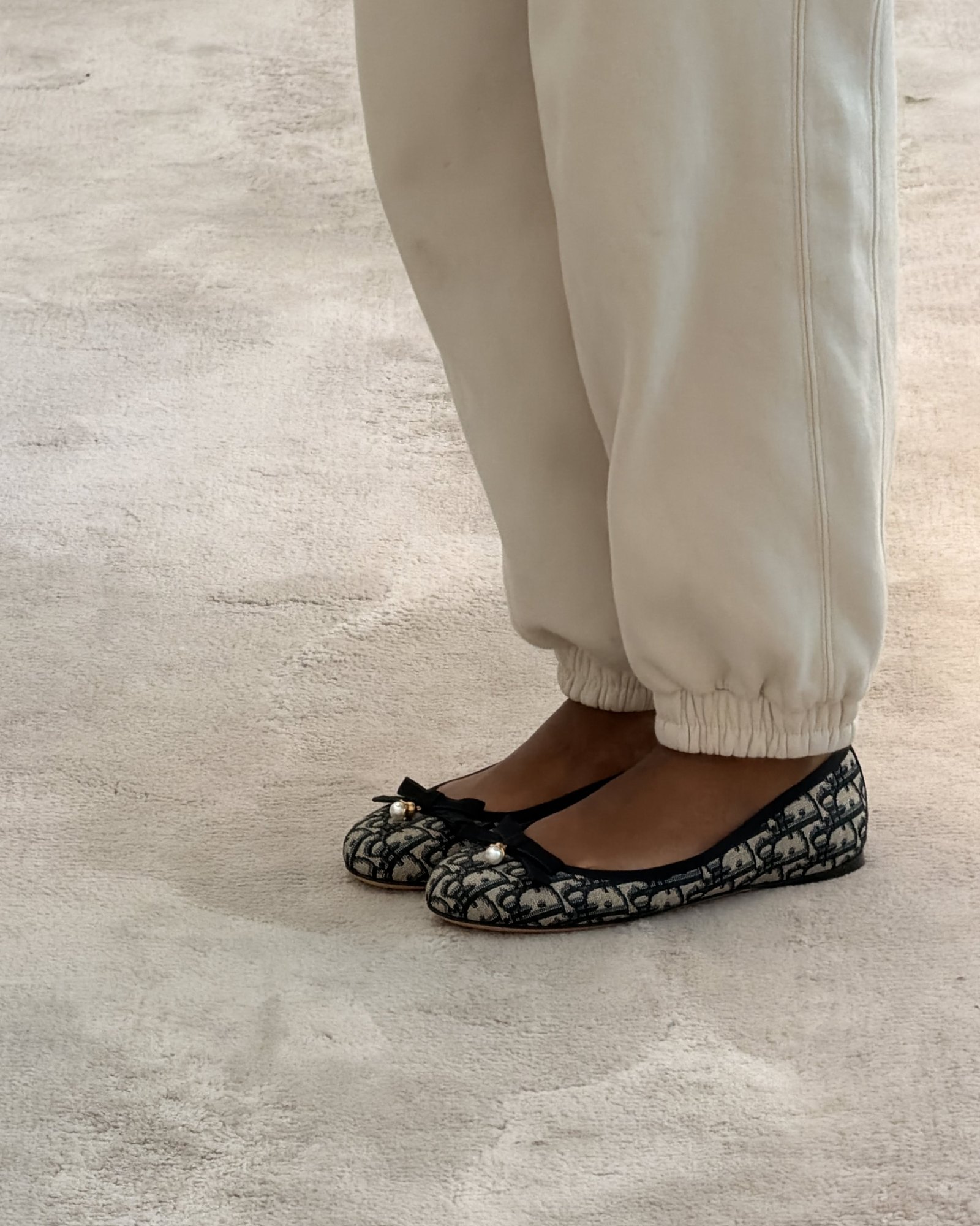 Close-up of Dior Oblique ballet flats worn with cream joggers