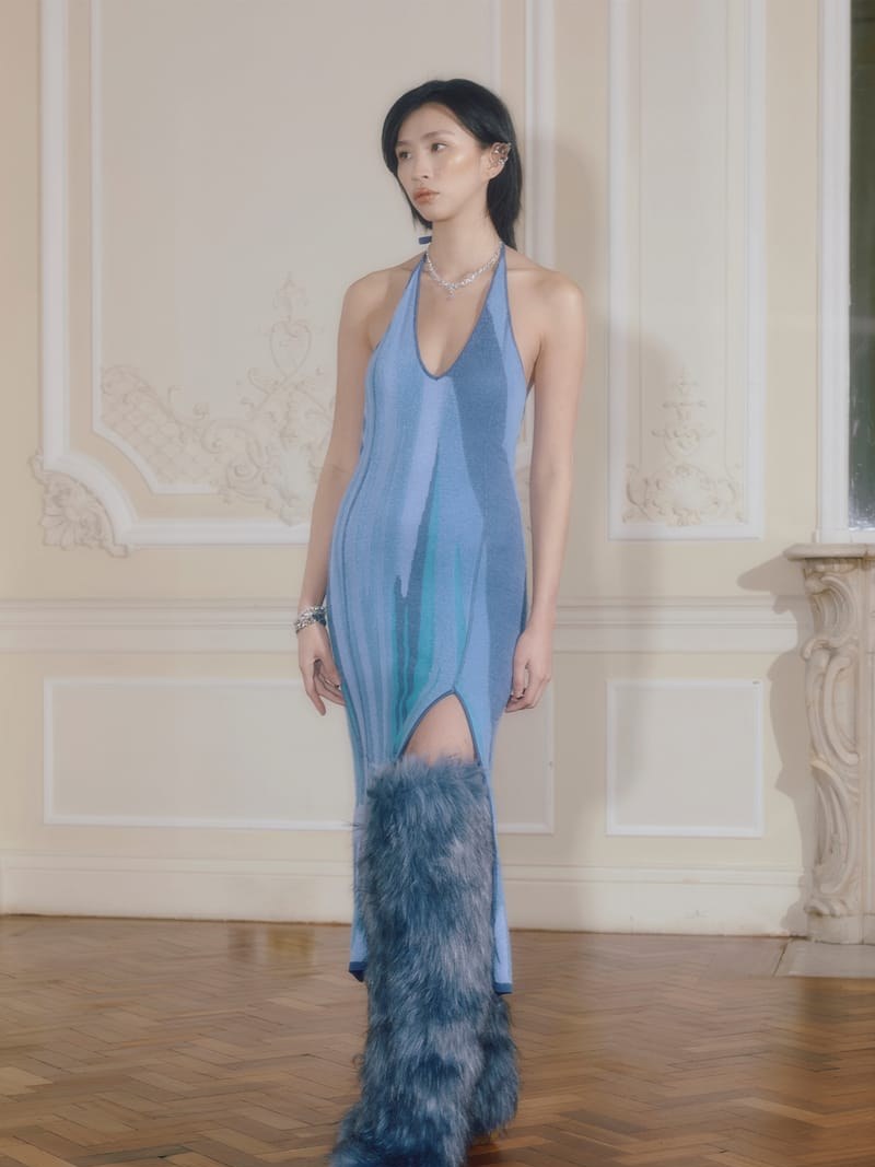 Model in a blue House of Sunny halter dress and furry leg warmers in a historic interior