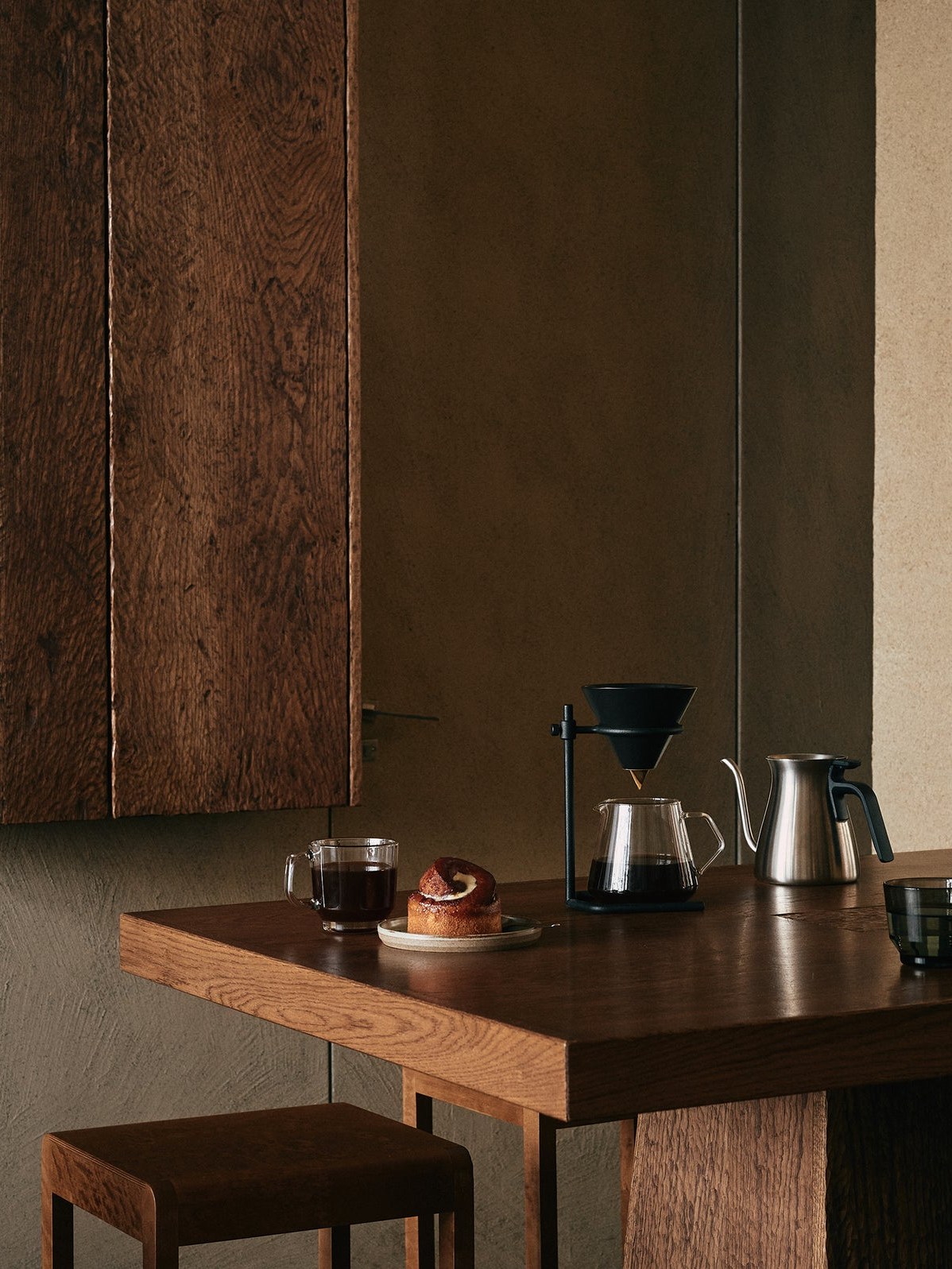 Coffee tools and glasses on a dark wooden table in a calm interior