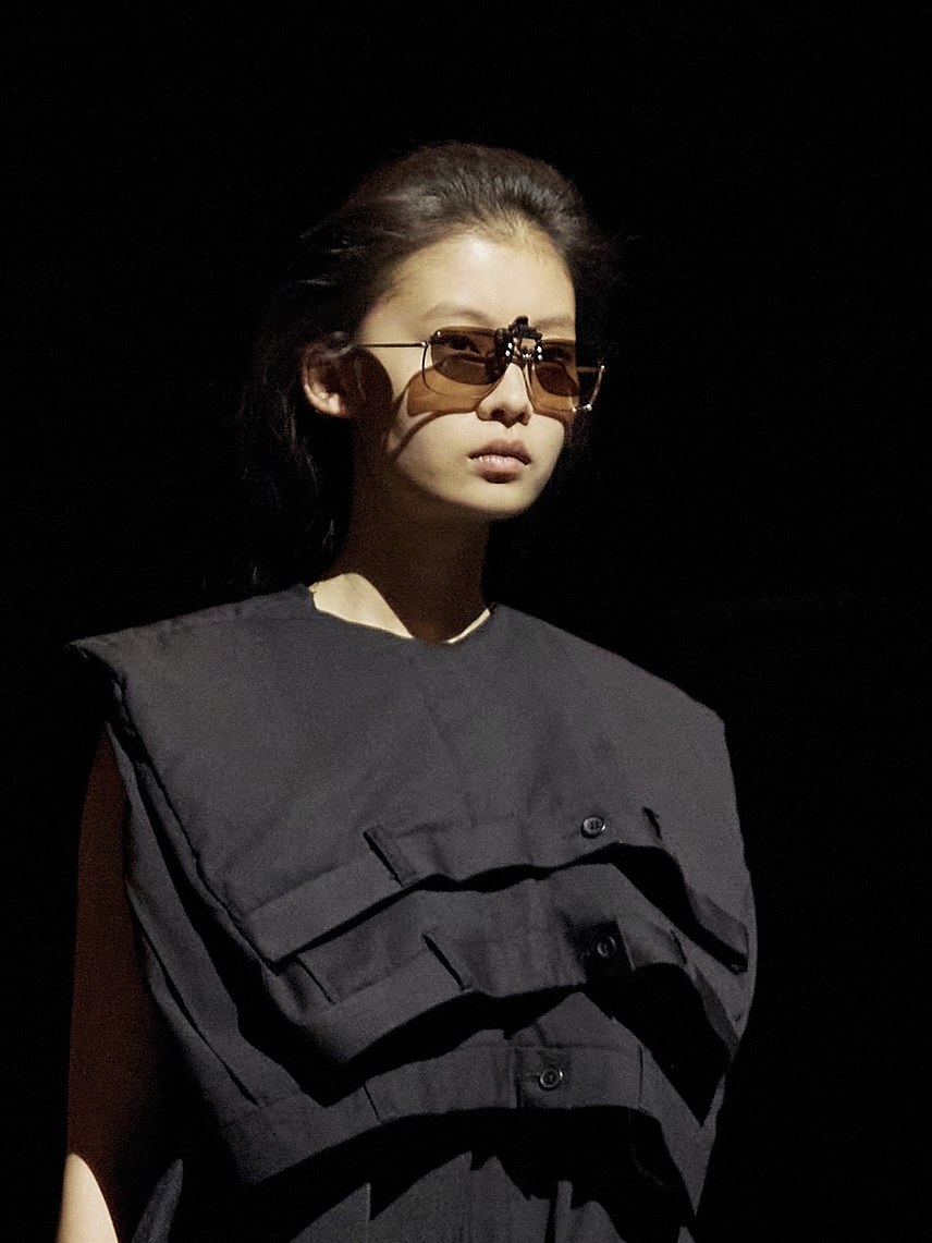 Model in a sculptural black look and Chimi sunglasses against a dark studio backdrop