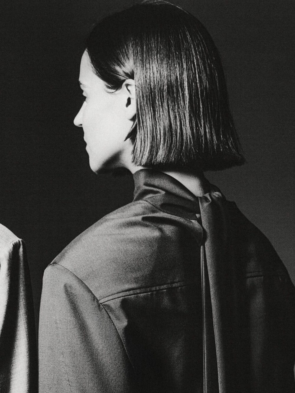 Model in dark tailoring shown in profile in a monochrome campaign