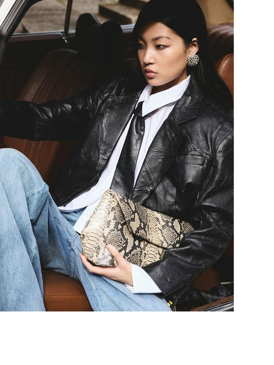 Model in a leather jacket and jeans seated in a car