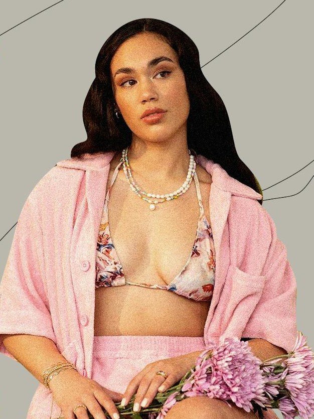 Model in a pink outfit wearing layered pearl and beaded necklaces