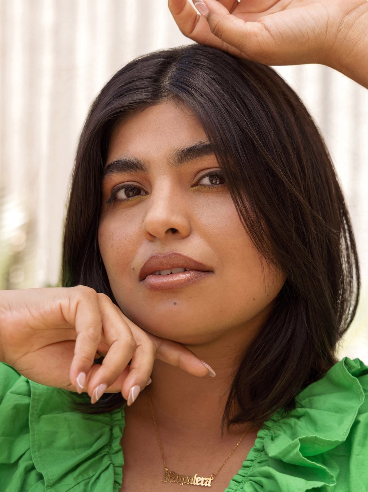 Model with dark hair wearing a green ruffled top in a sunlit portrait