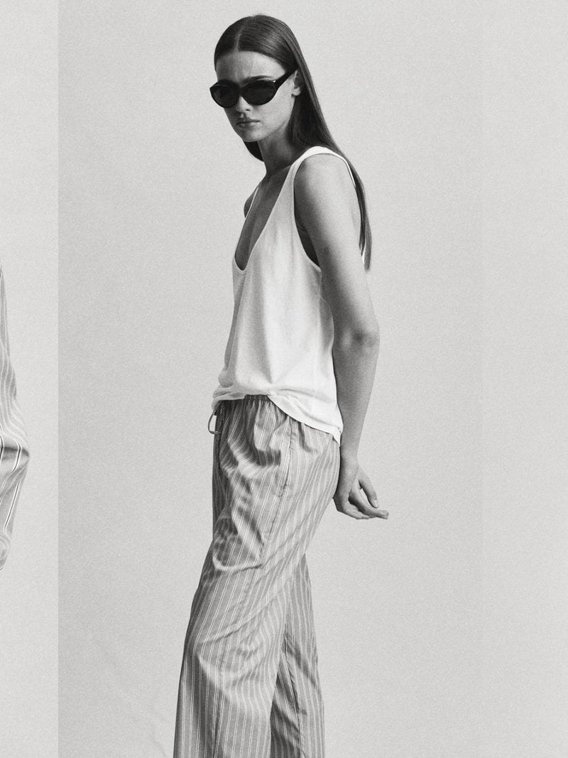 Model in a striped CLYQUE top and trousers in a monochrome studio