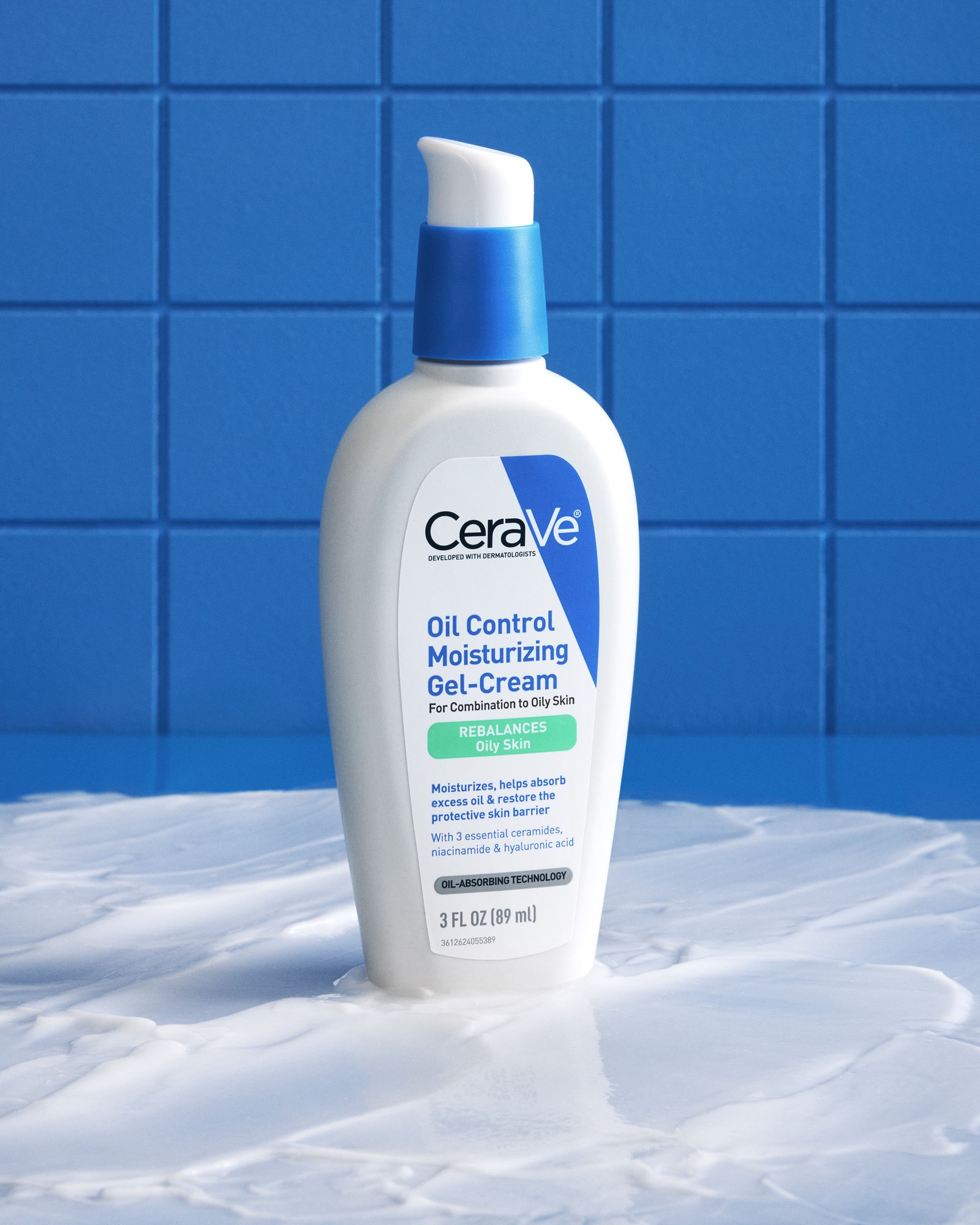 CeraVe Oil Control Moisturizing Gel-Cream pump bottle standing in a pool of white cream against a blue tiled wall