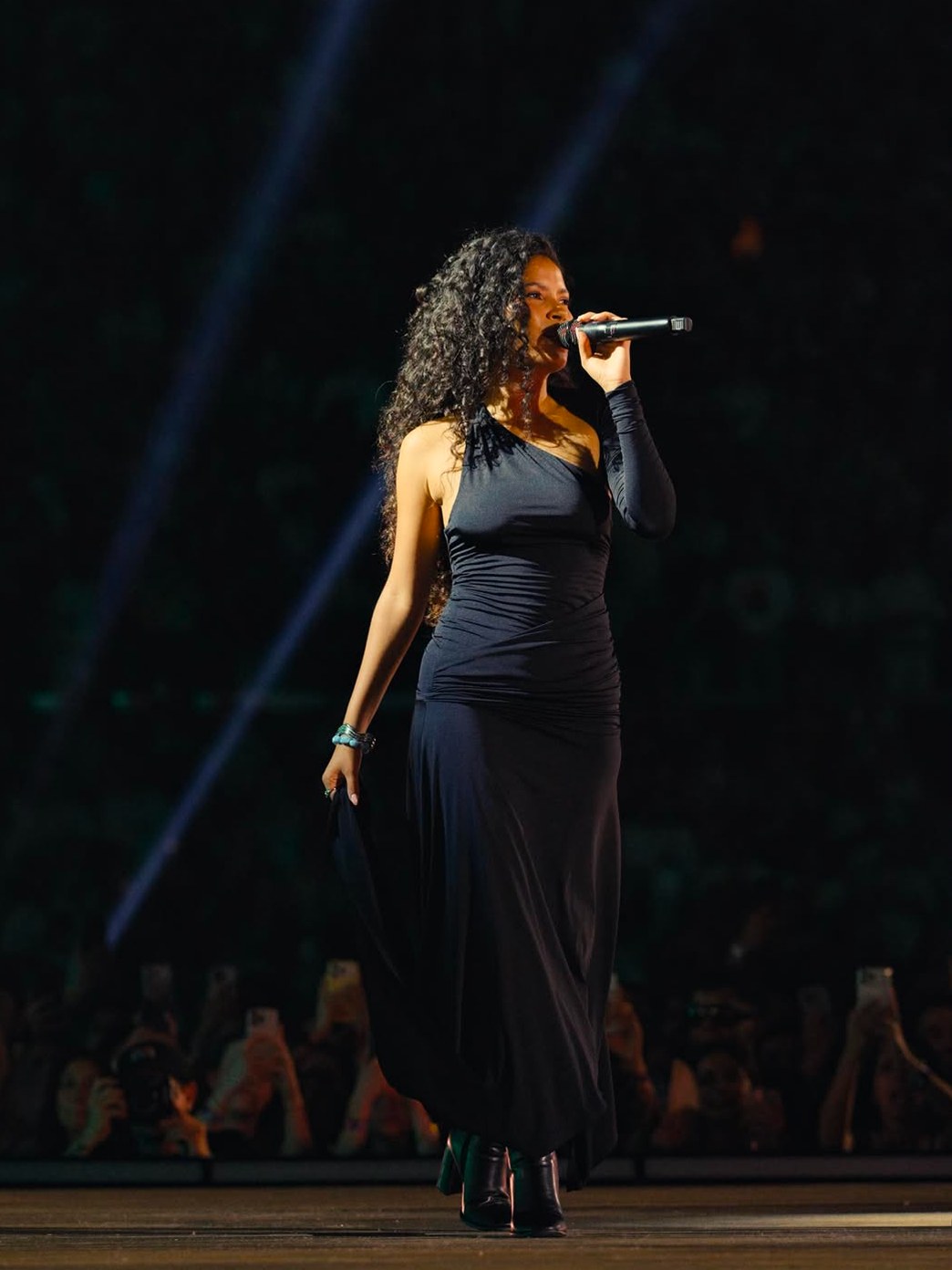 Singer in a black one-shoulder dress performing onstage