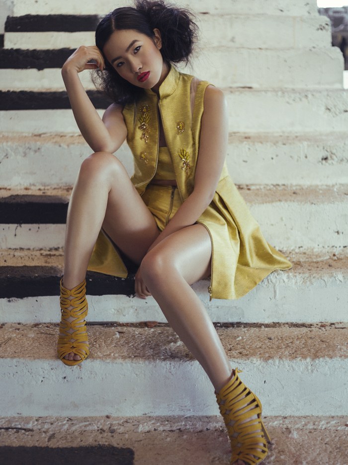 Model in a gold outfit seated on outdoor steps