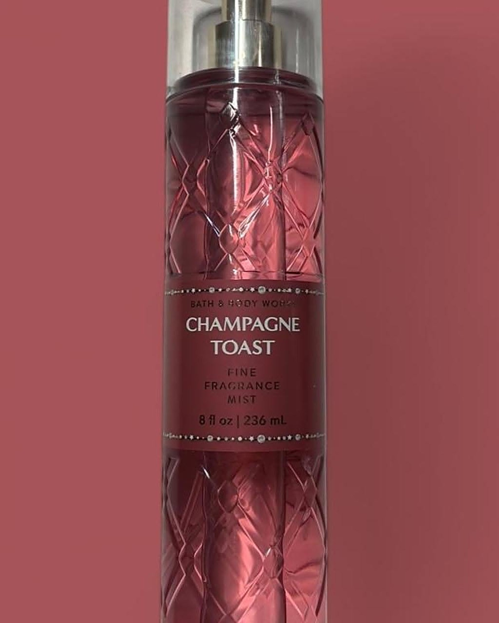Bottle of Bath & Body Works Champagne Toast Fine Fragrance Mist in pink glass against a dusty rose background