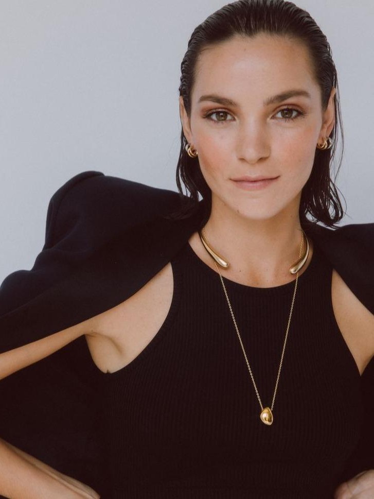 Model in black wearing a gold double chain choker and earrings