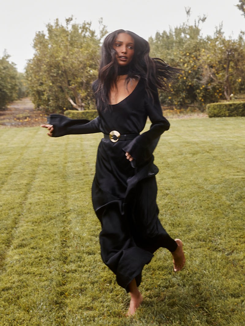 Woman in a black dress walking across a green lawn in an outdoor campaign