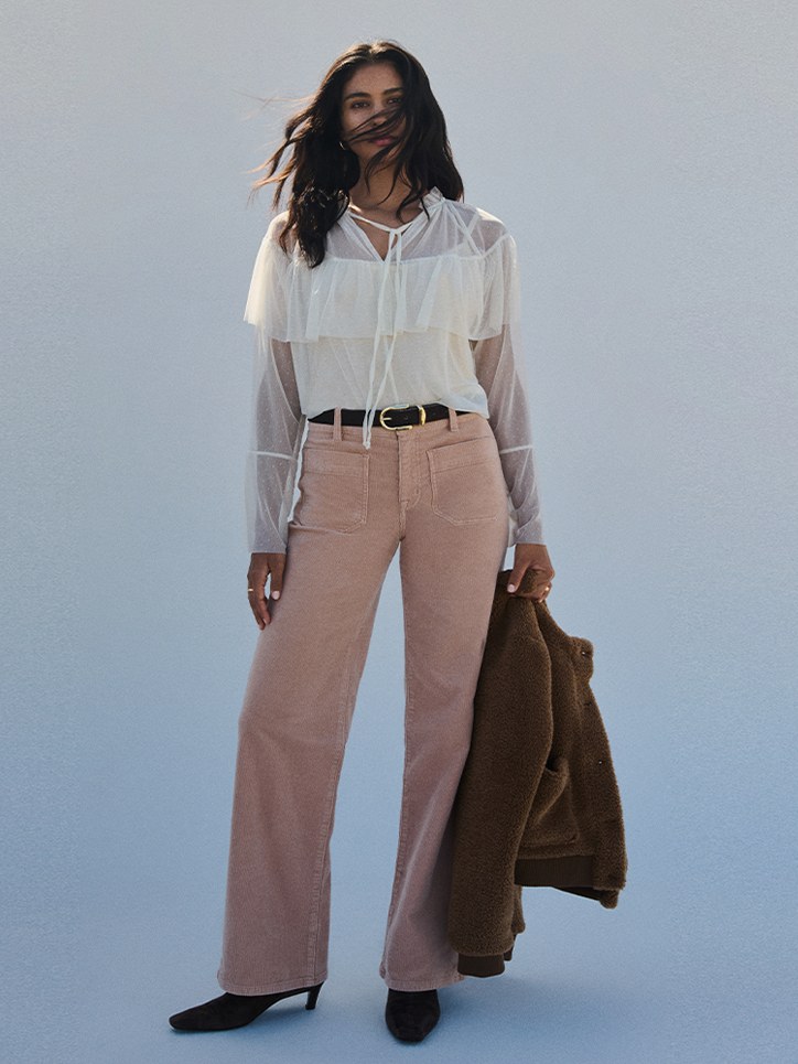 Model in an ivory blouse and rose trousers on a cool blue campaign set