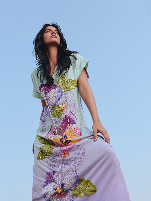 Model in an embroidered lavender dress against a blue studio sky