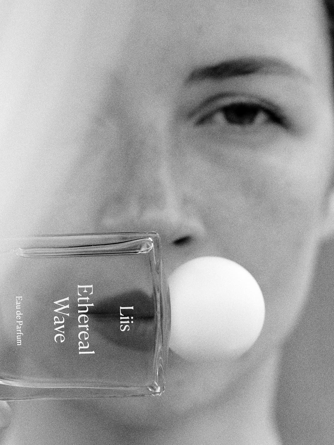Monochrome close-up portrait with a Liis Ethereal Wave bottle held near the face