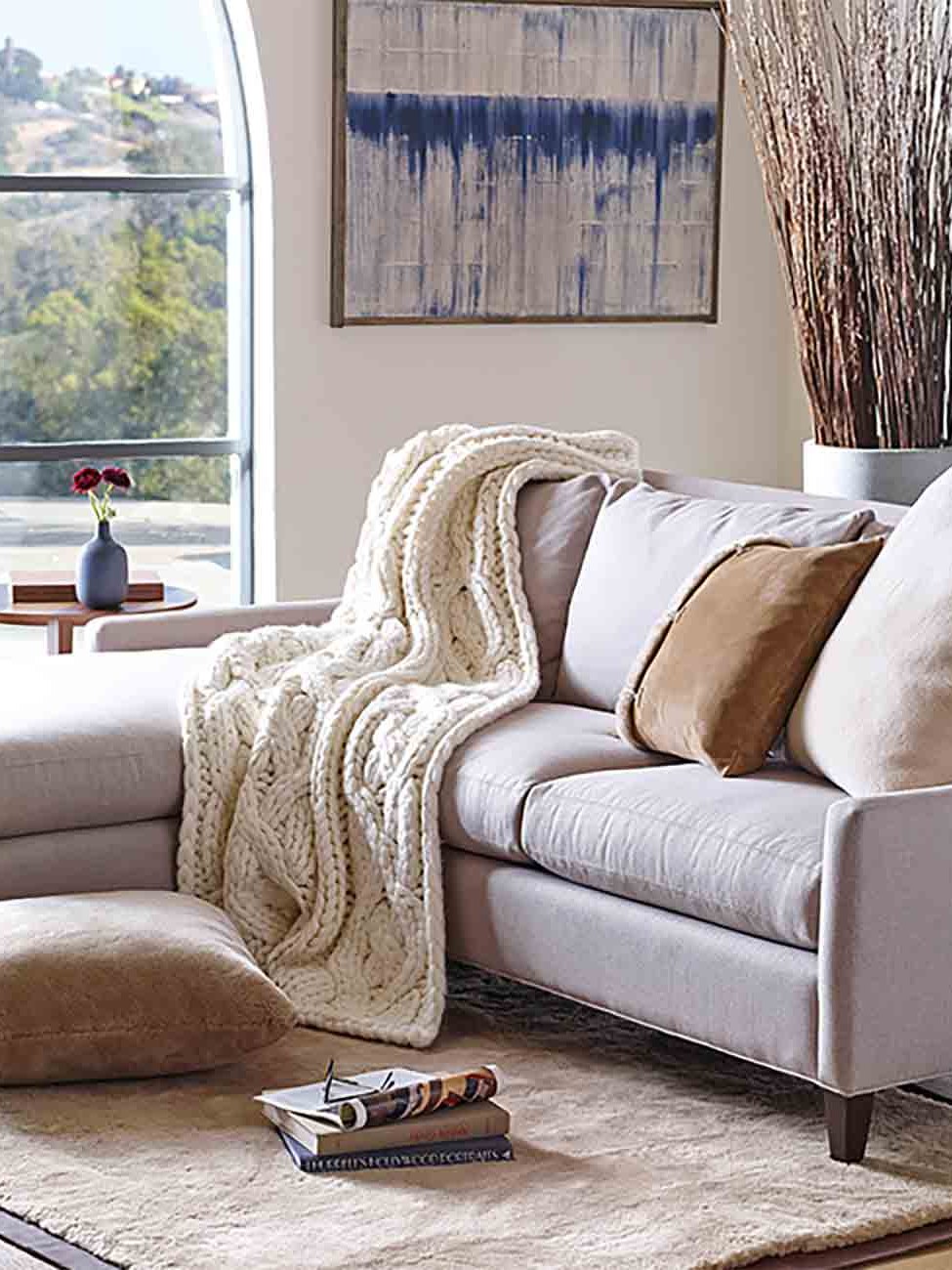 Chunky knit throw draped over a pale sofa