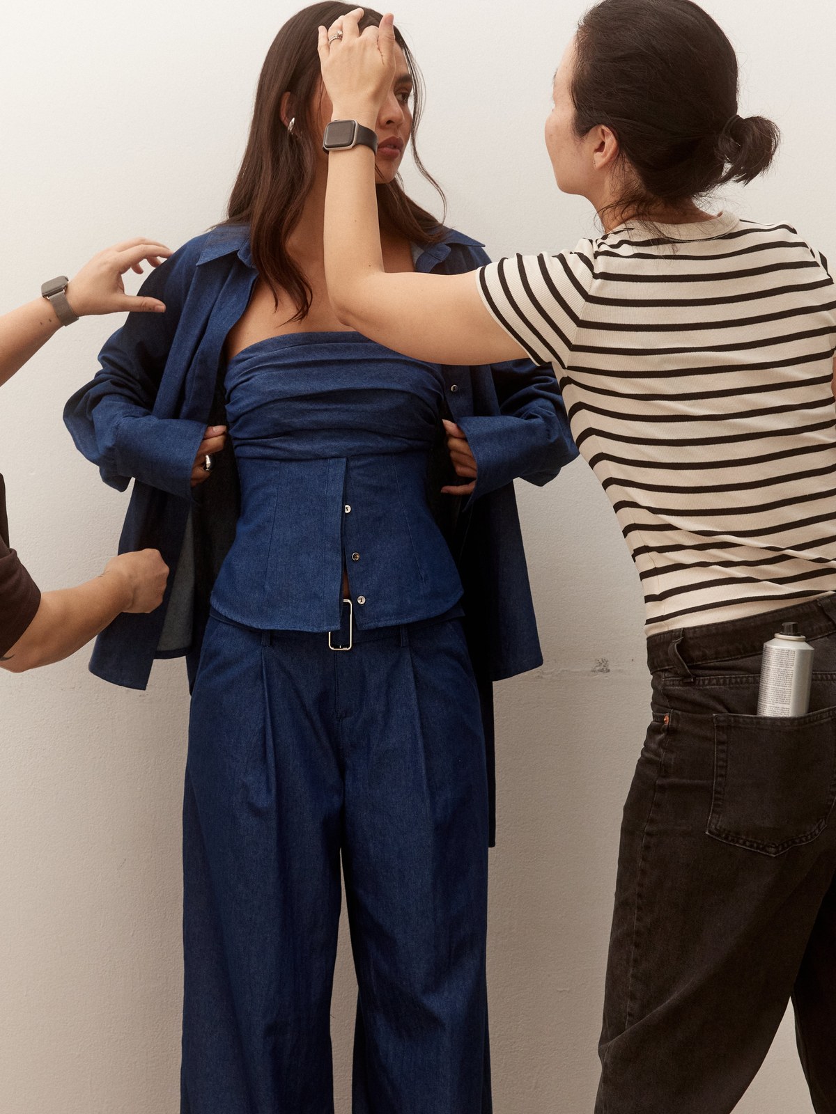 Stylist adjusts a model in a blue denim outfit during a SOVERE shoot
