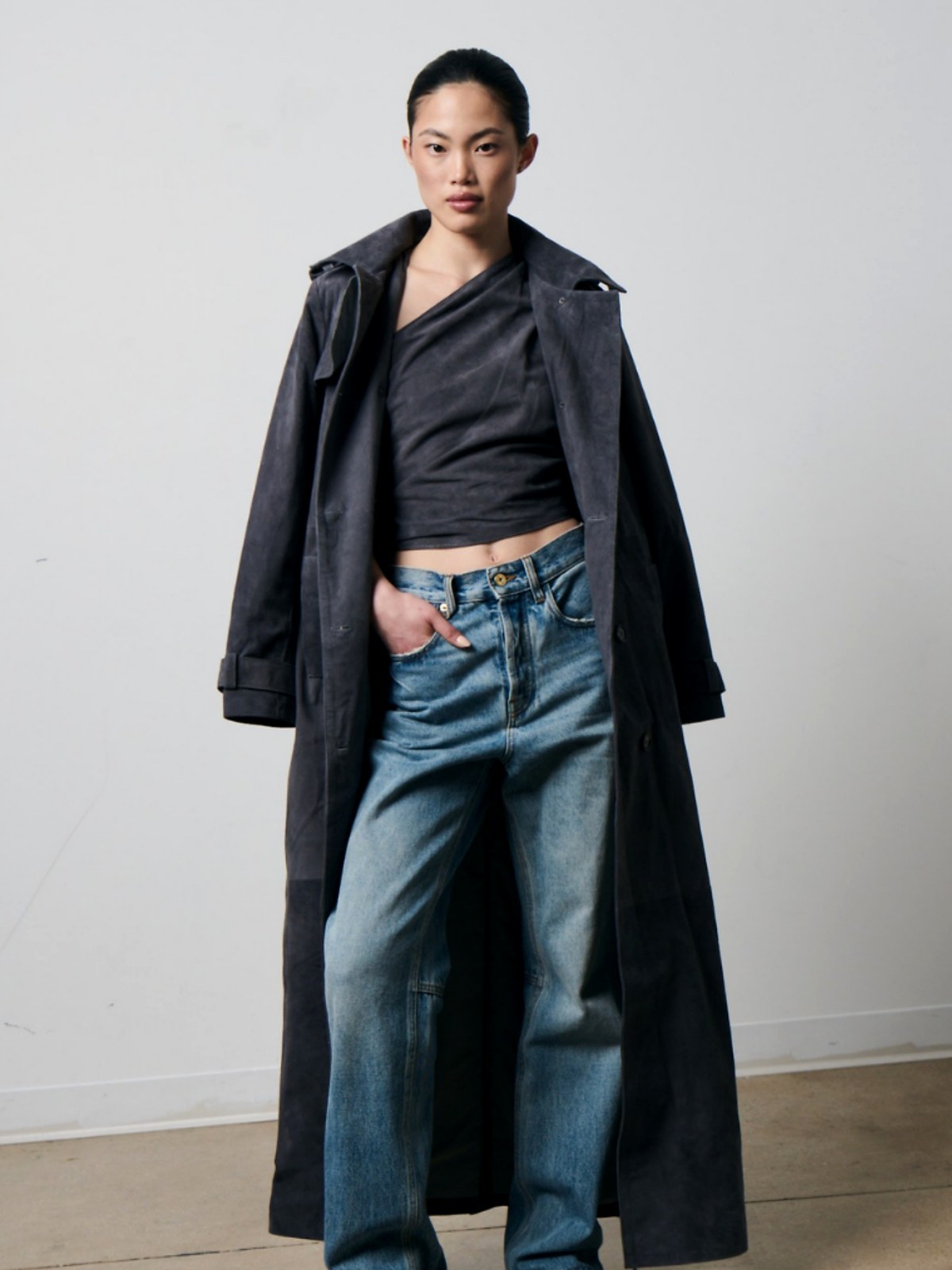 Model in a long charcoal coat over blue denim