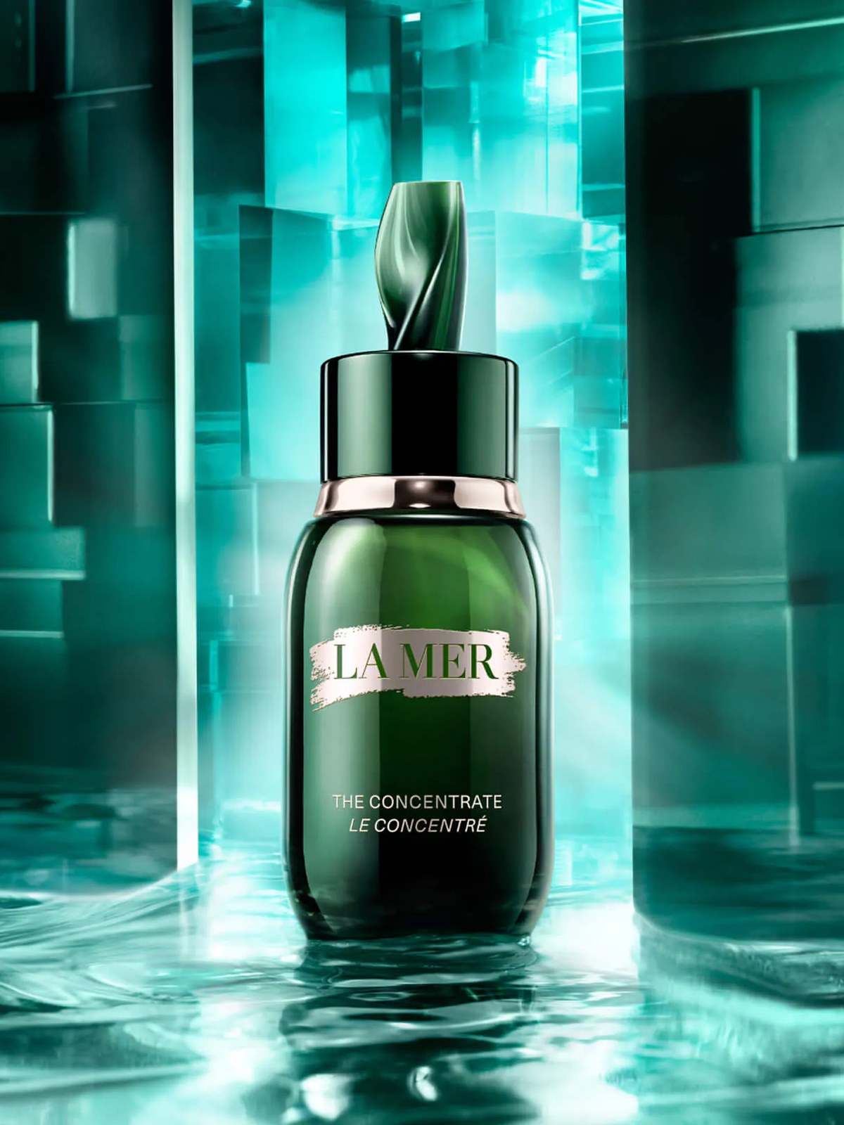 La Mer Concentrate bottle standing on water in a teal glass block set