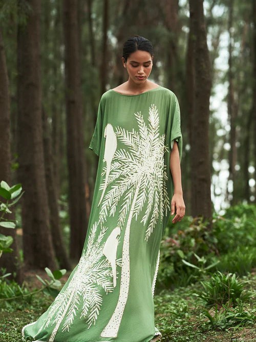 Model in a green botanical gown walking through a forest
