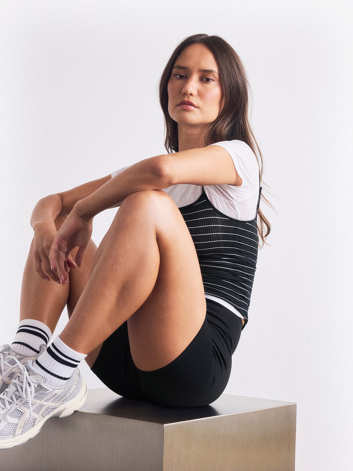Model in black lounge activewear seated on a studio plinth