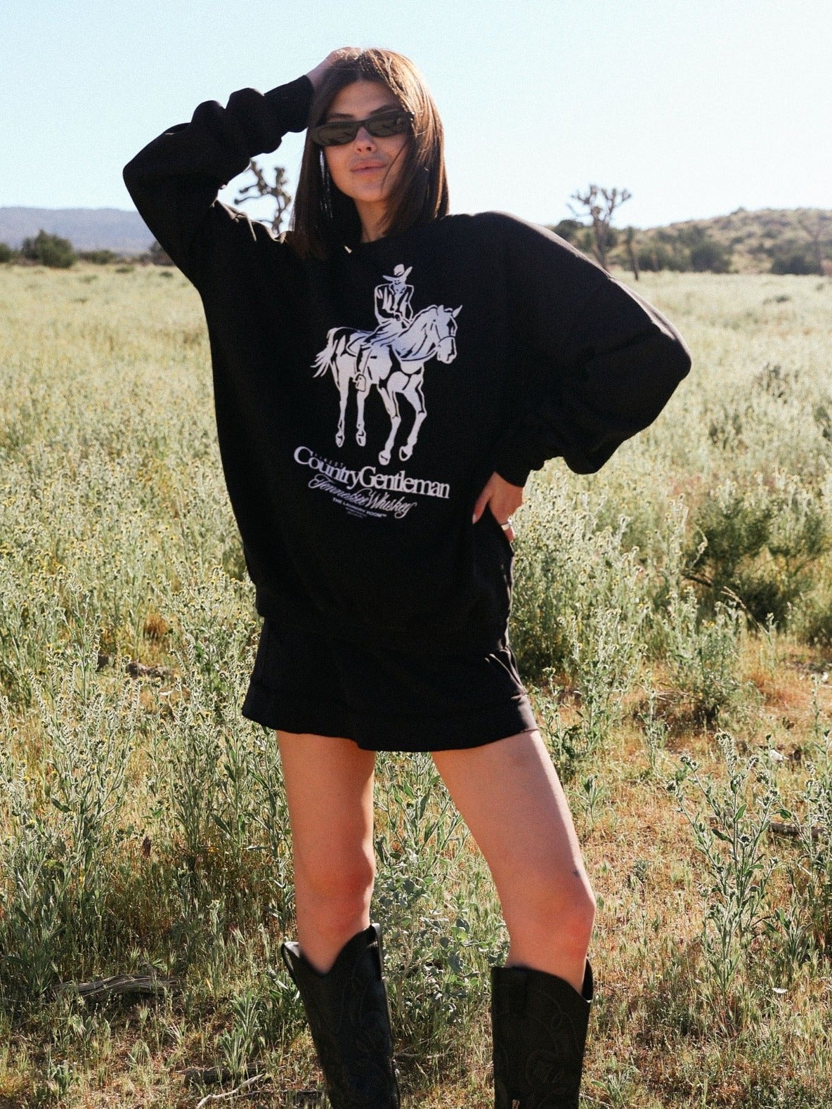 Model in a black Western graphic hoodie standing in a field