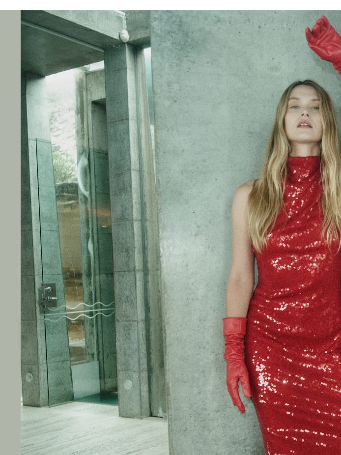 Model in a red sequin dress and long gloves reflected in a mirror