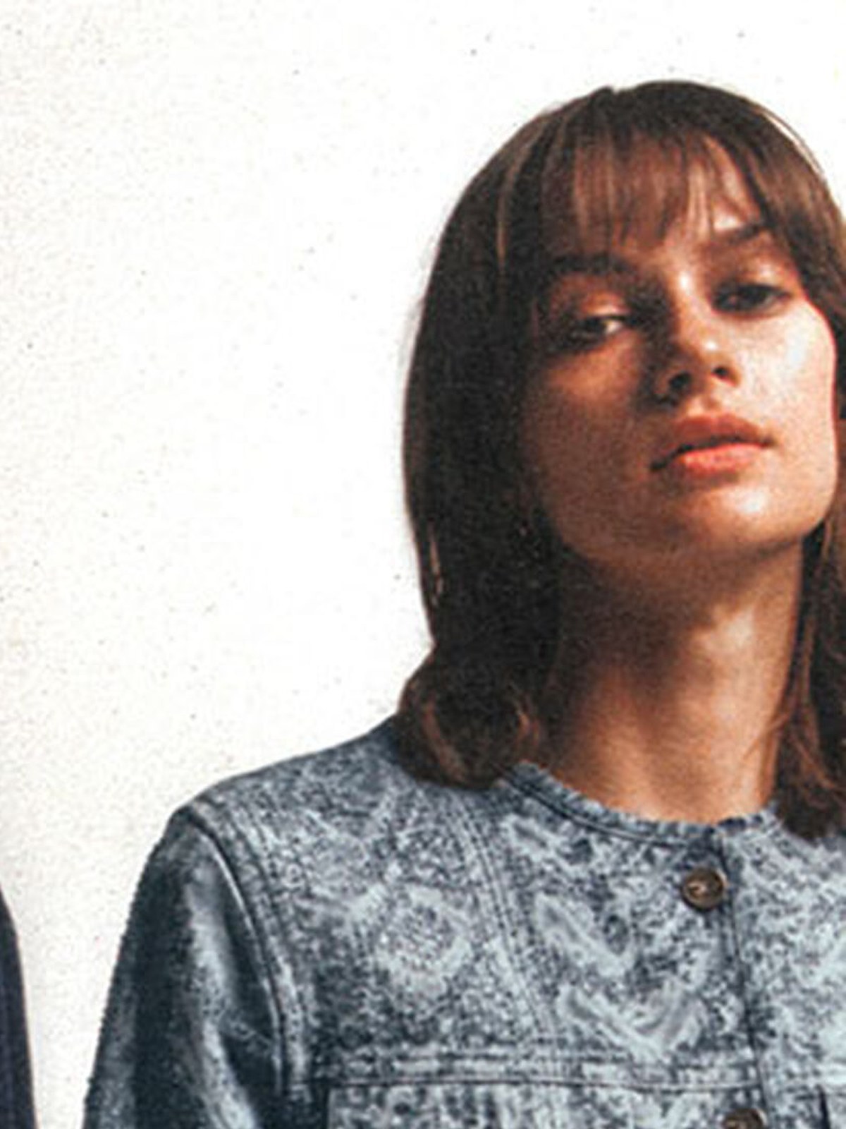 Model in a patterned denim jacket against a white wall
