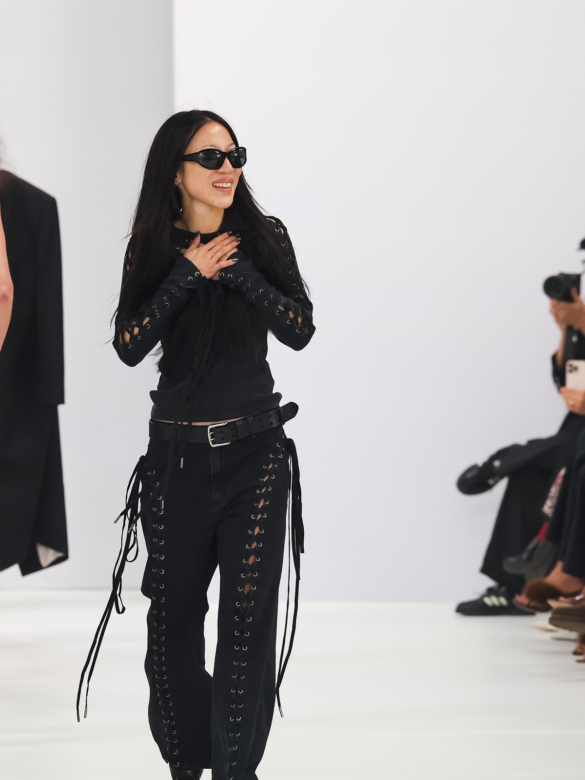 Model in black walking a runway before seated guests