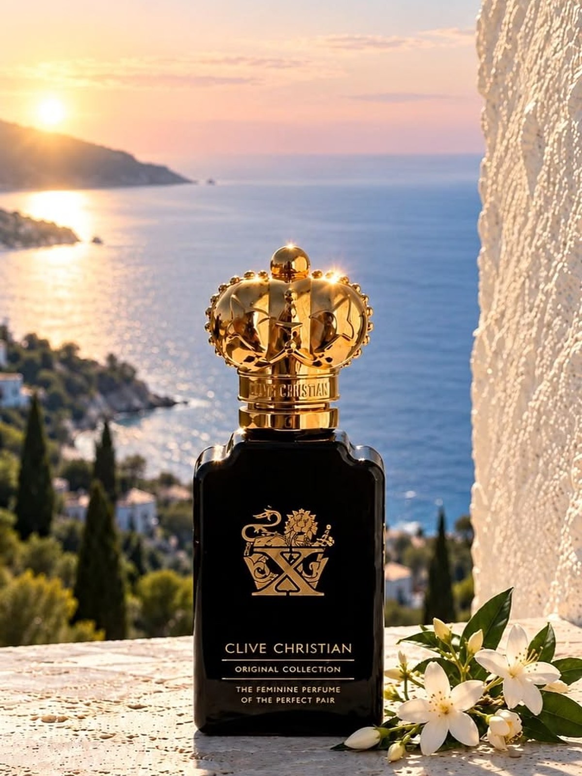 Clive Christian black crown bottle on a stone ledge above the sea at sunset