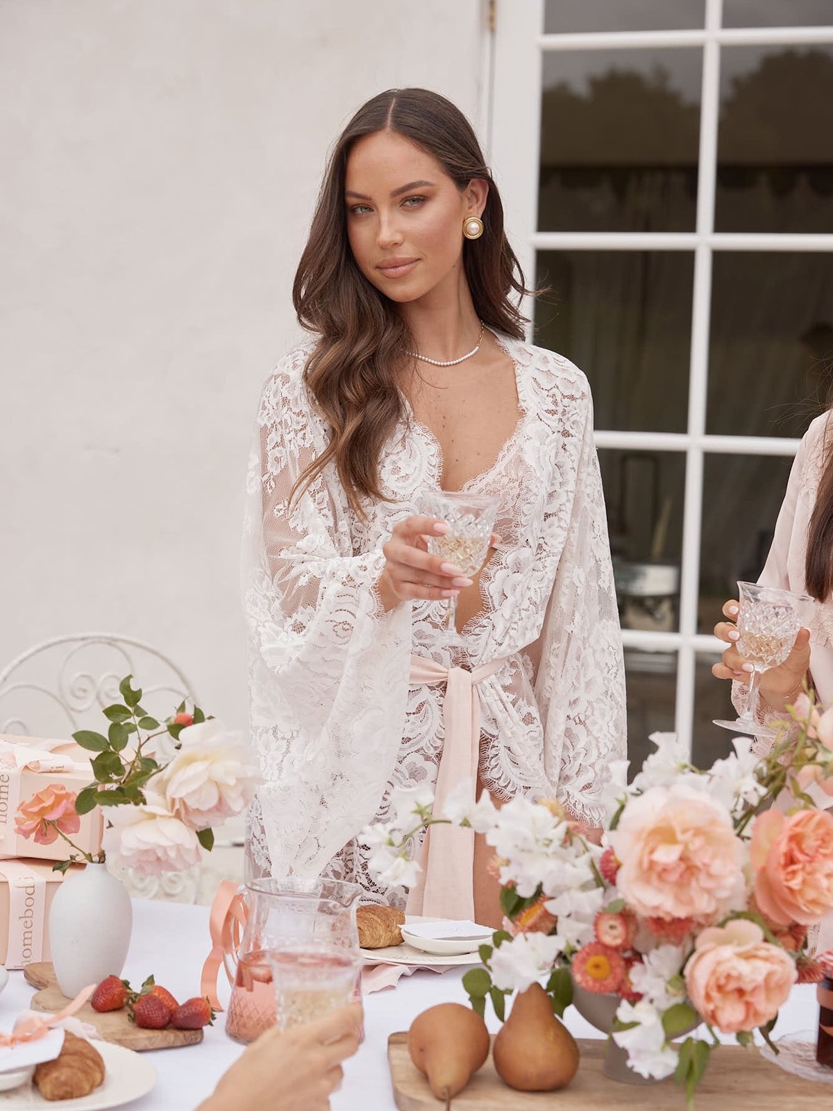 Woman in a lace robe at a flower-filled breakfast table