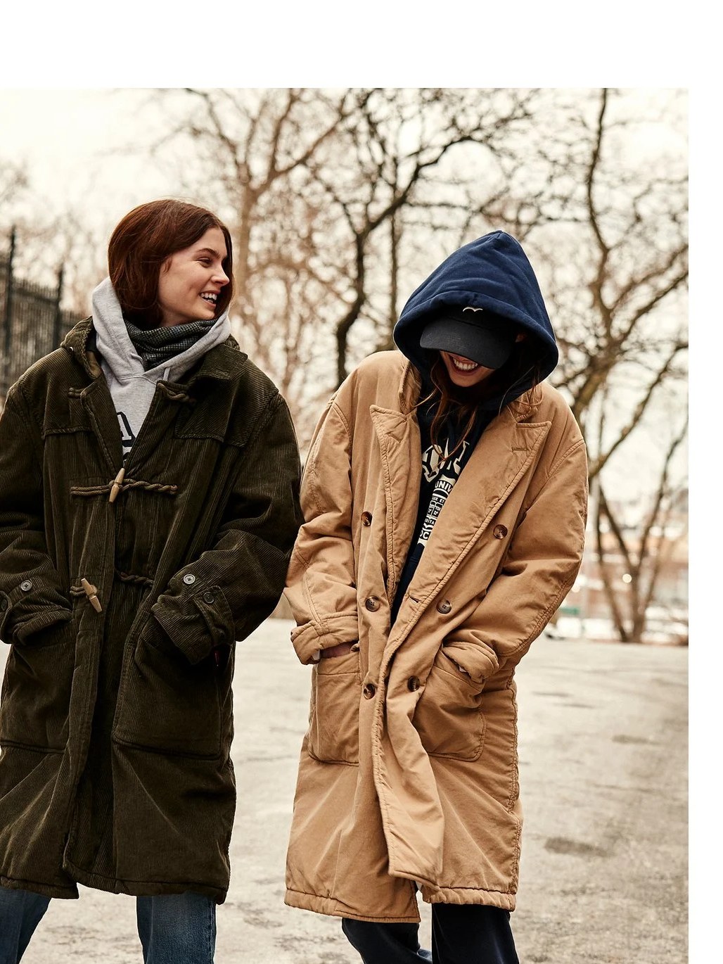 Two models in long coats on a tree-lined street in the Denimist Fall Winter campaign